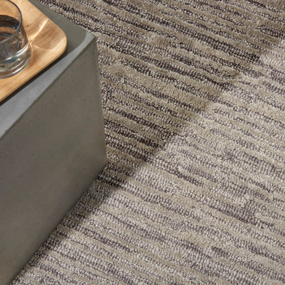 Grey concrete block table with a light wood tray and a glass of water on a beige striped rug.