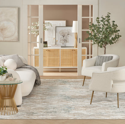 Neutral living room with white lounge chairs, rattan cabinet, glass-top table, gold base, potted tree and area rug.