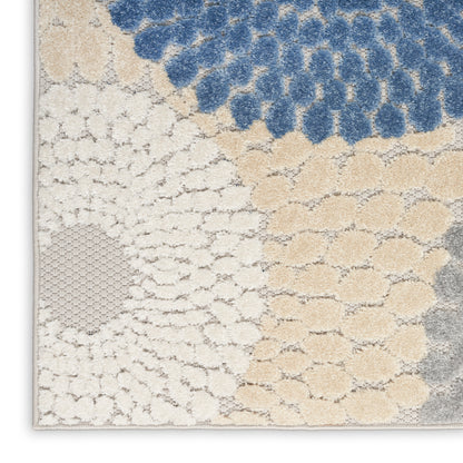 Close-up of a tufted rug with blue clusters atop ivory and beige circular patterns, light gray border.