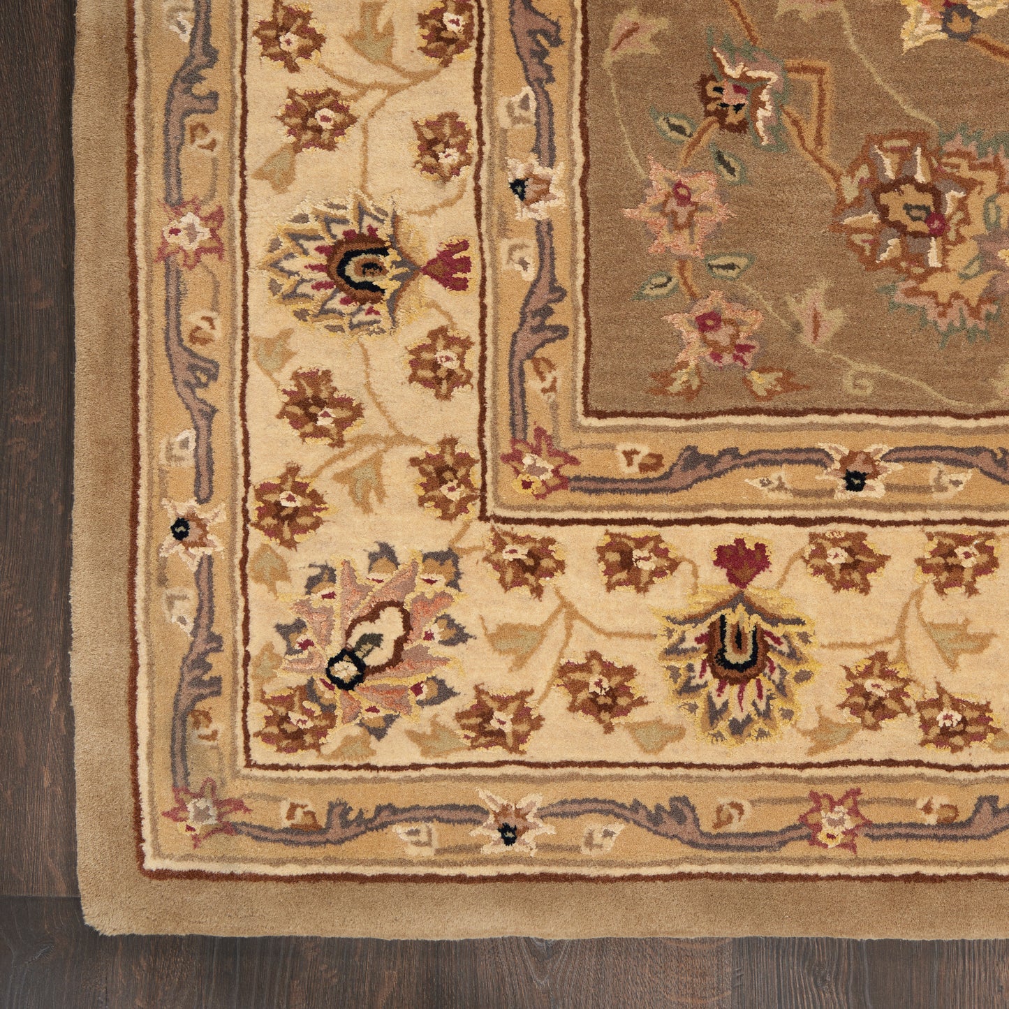 Ornate oriental-style rug in cream and beige with brown floral border on dark wooden floor.