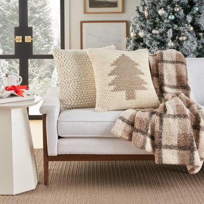 Decorative ivory beige 20x20 pillow on a cream sofa with a knitted-tree pattern.