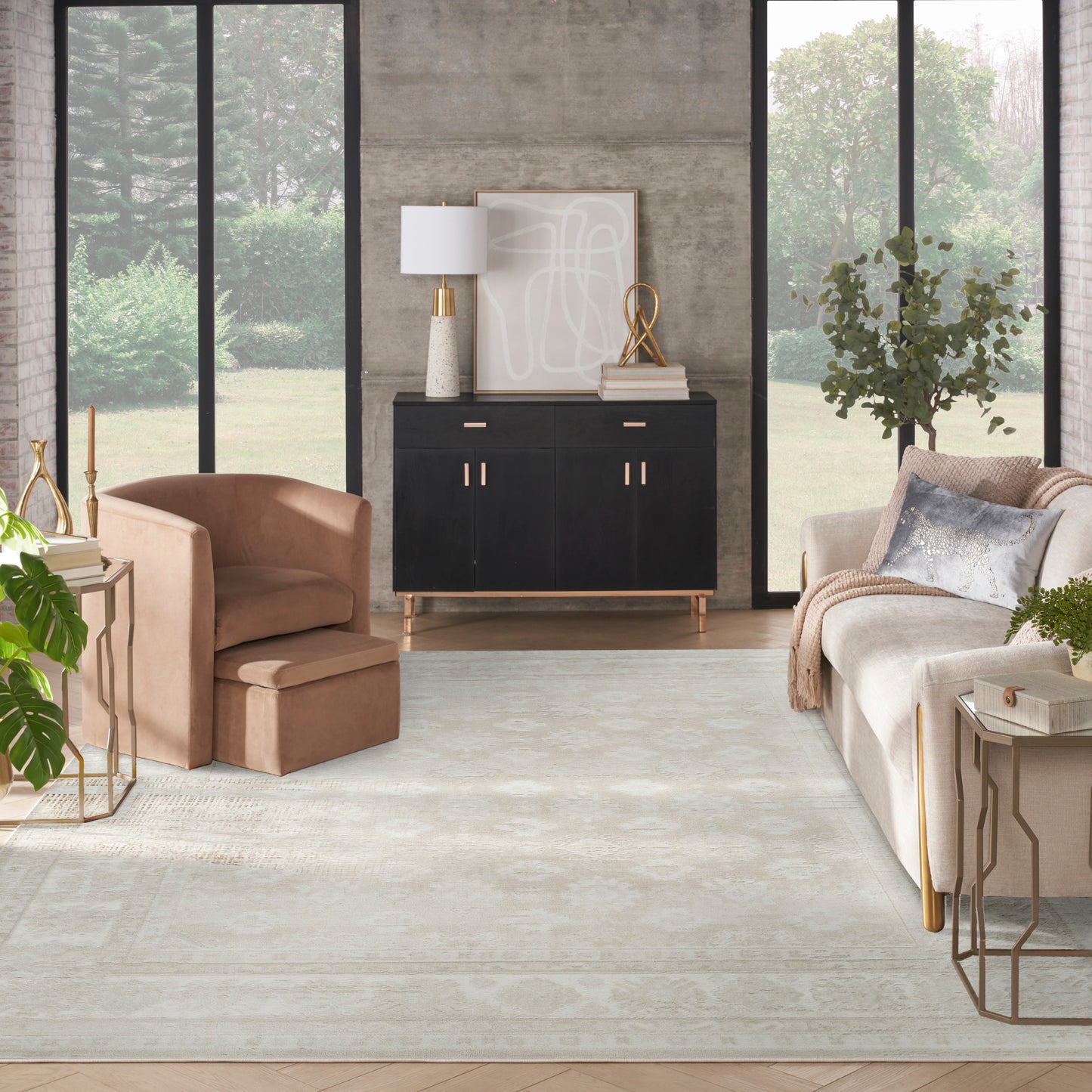 Modern living room with a black cabinet, beige velvet armchair, light sofa, rug, gold accents, windows, greenery.