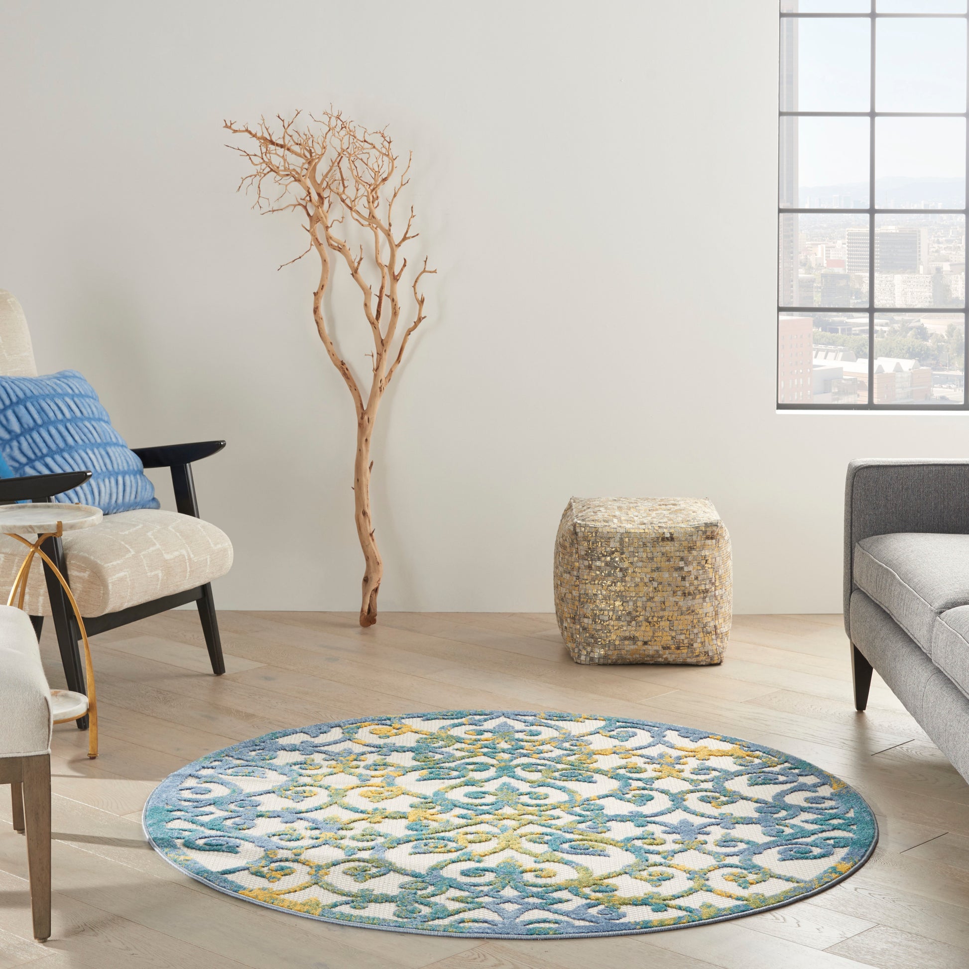 Round blue-teal patterned rug with yellow accents on light wood floor in a modern living room.