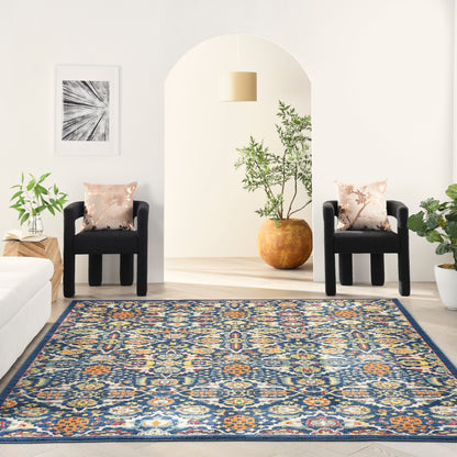 Rectangular oriental-inspired rug in blues, oranges and creams in a bright living room with two black chairs and plants.