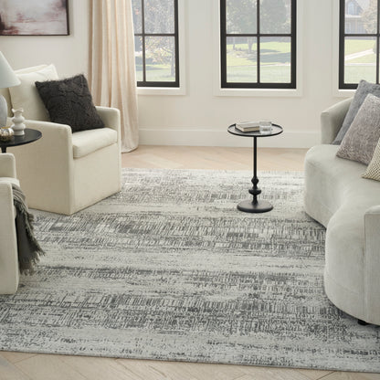 Bright living room with cream armchairs, gray rug, round black pedestal tables, beige curtains, black-framed windows.