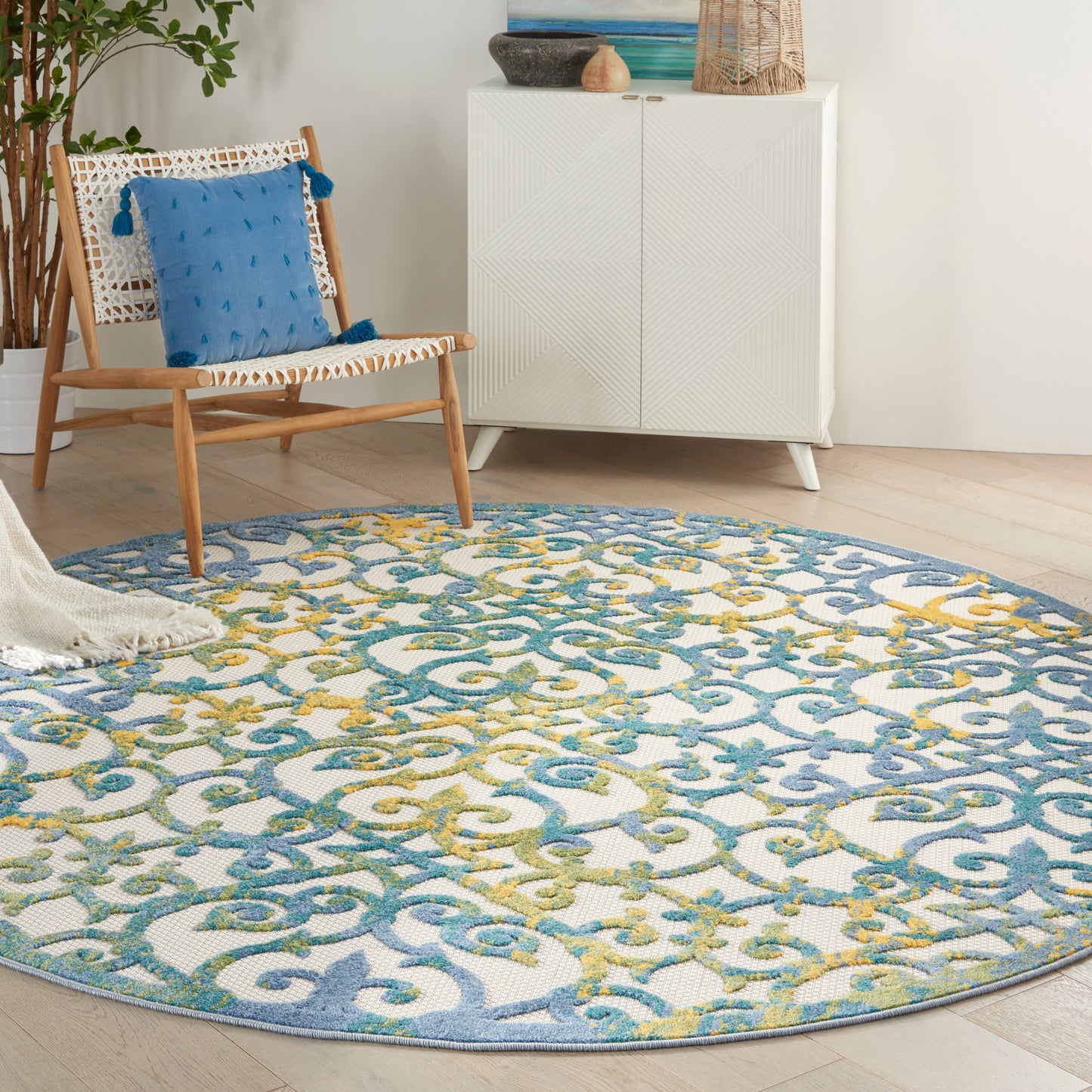 Round rug with blue, teal and yellow scrolling motif; coastal boho living room decor.