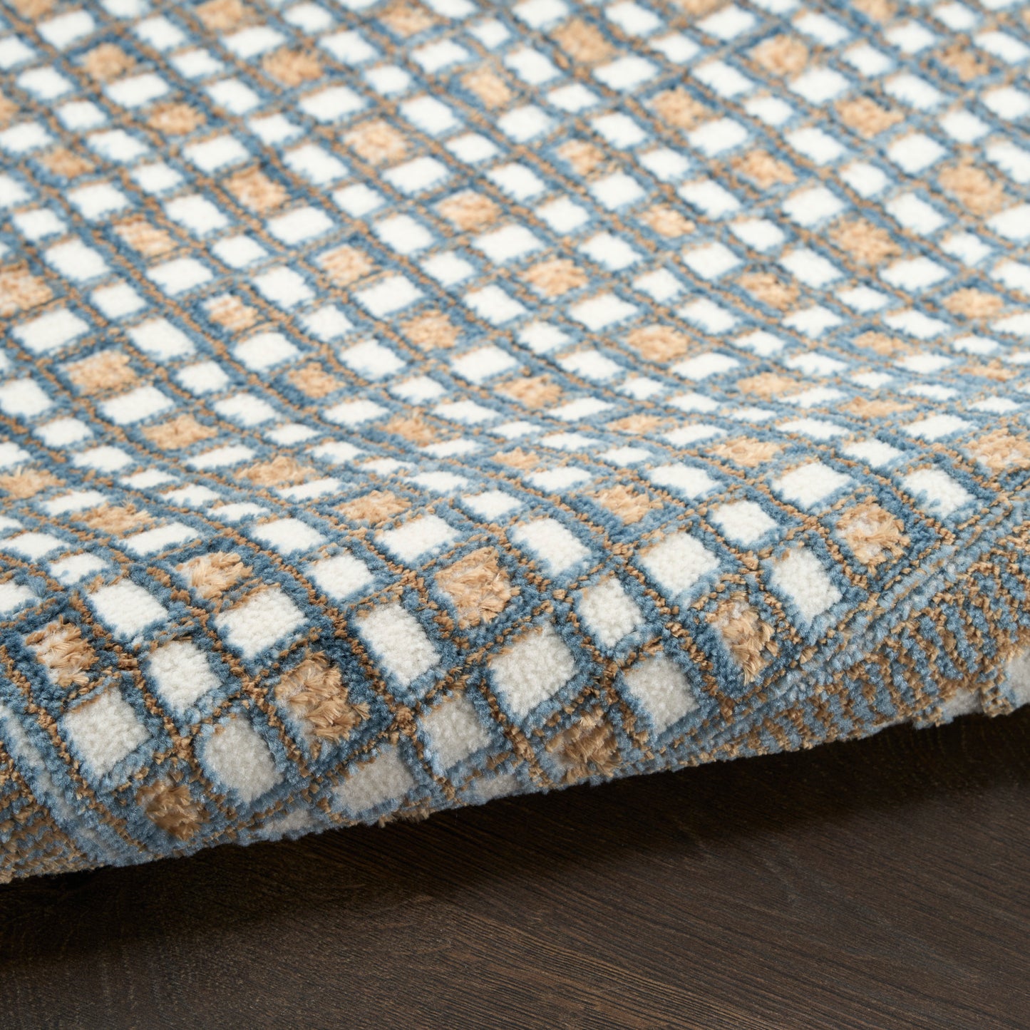 Rectangular tufted rug with a blue-gray, white and tan checkered grid pattern; soft, cozy floor decor.