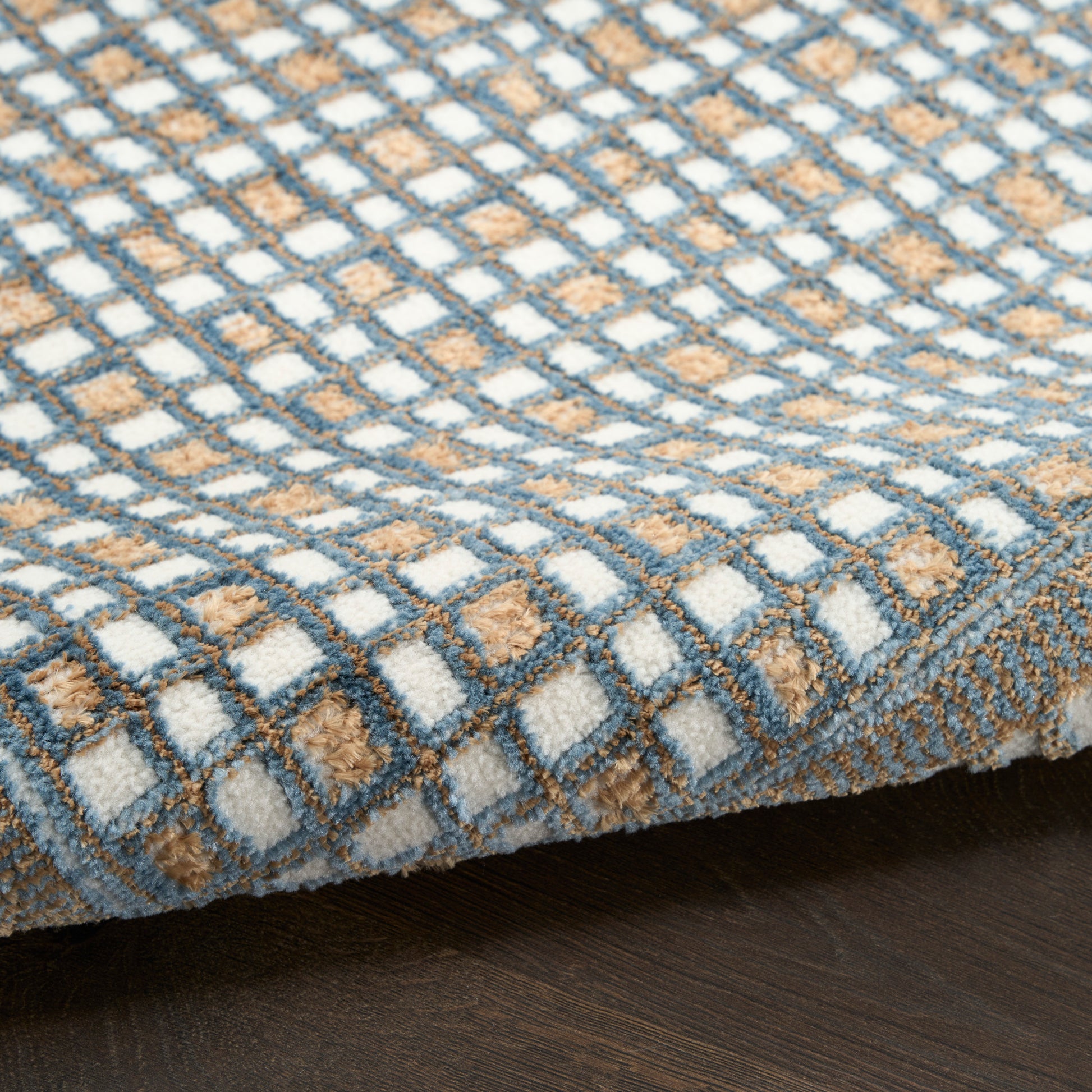Rectangular tufted rug with a blue-gray, white and tan checkered grid pattern; soft, cozy floor decor.