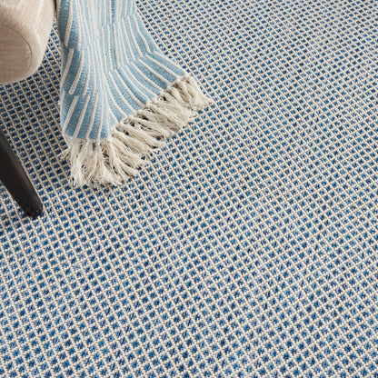 Blue and white woven checkered rug with fringe edging; light-blue striped throw draped over a chair leg.