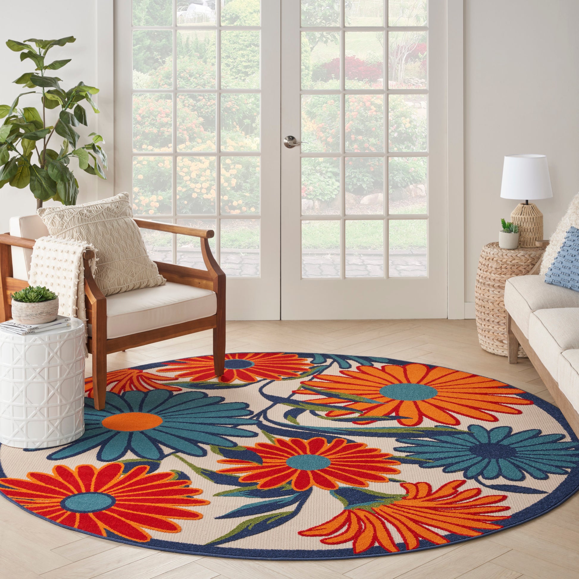 Round floral area rug in vibrant orange, teal & blue on cream; complements a cozy living room.