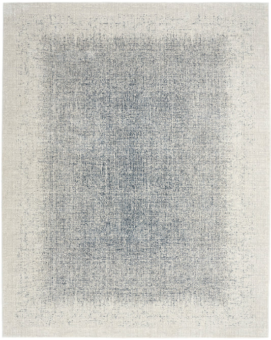 Rectangular beige area rug with a faded indigo center and distressed abstract pattern for modern living spaces.