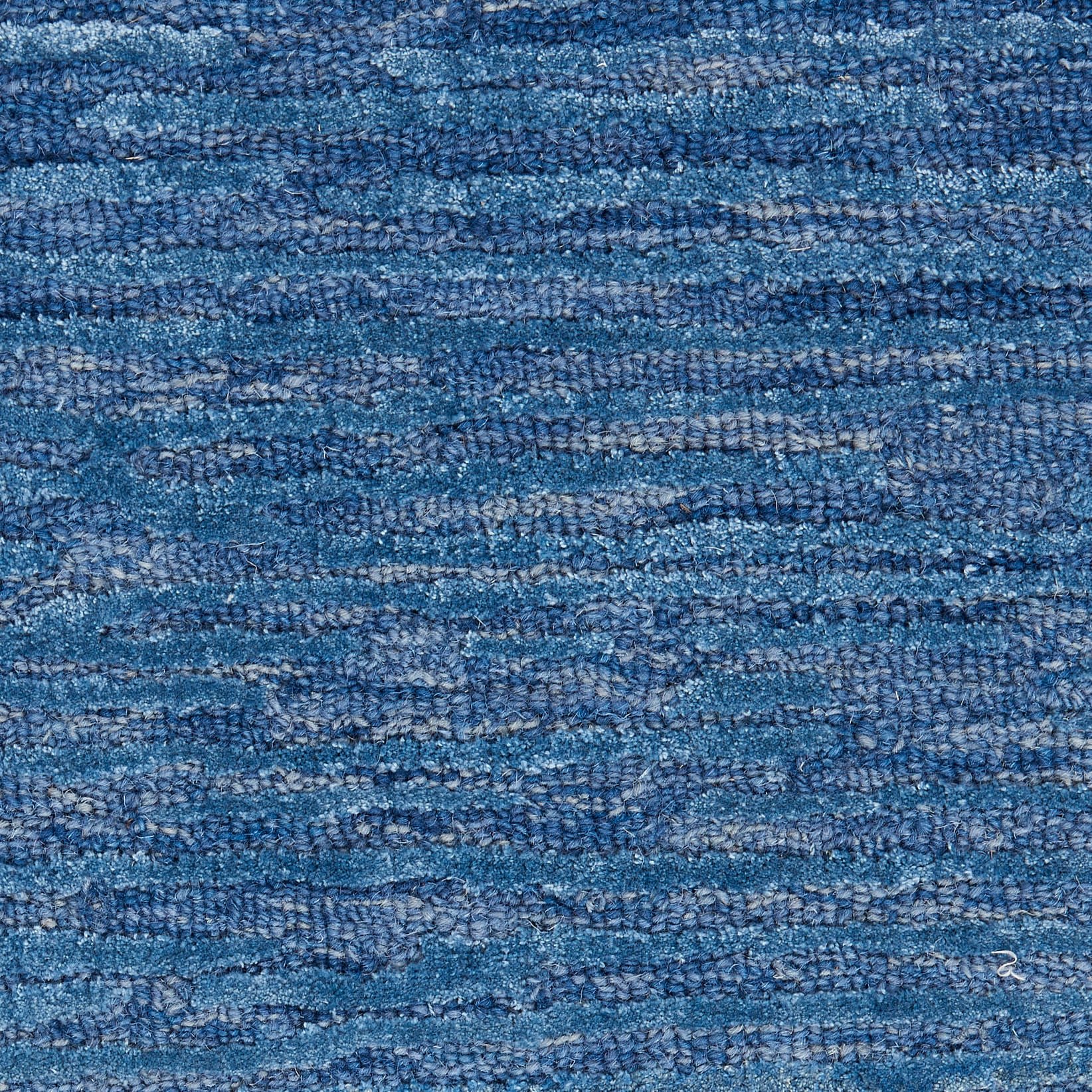 Blue textured woven rug with variegated shades and horizontal stripe pattern.
