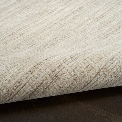 Beige, plush-area rug with textured pile and subtle pattern, folded edge on dark wood floor.