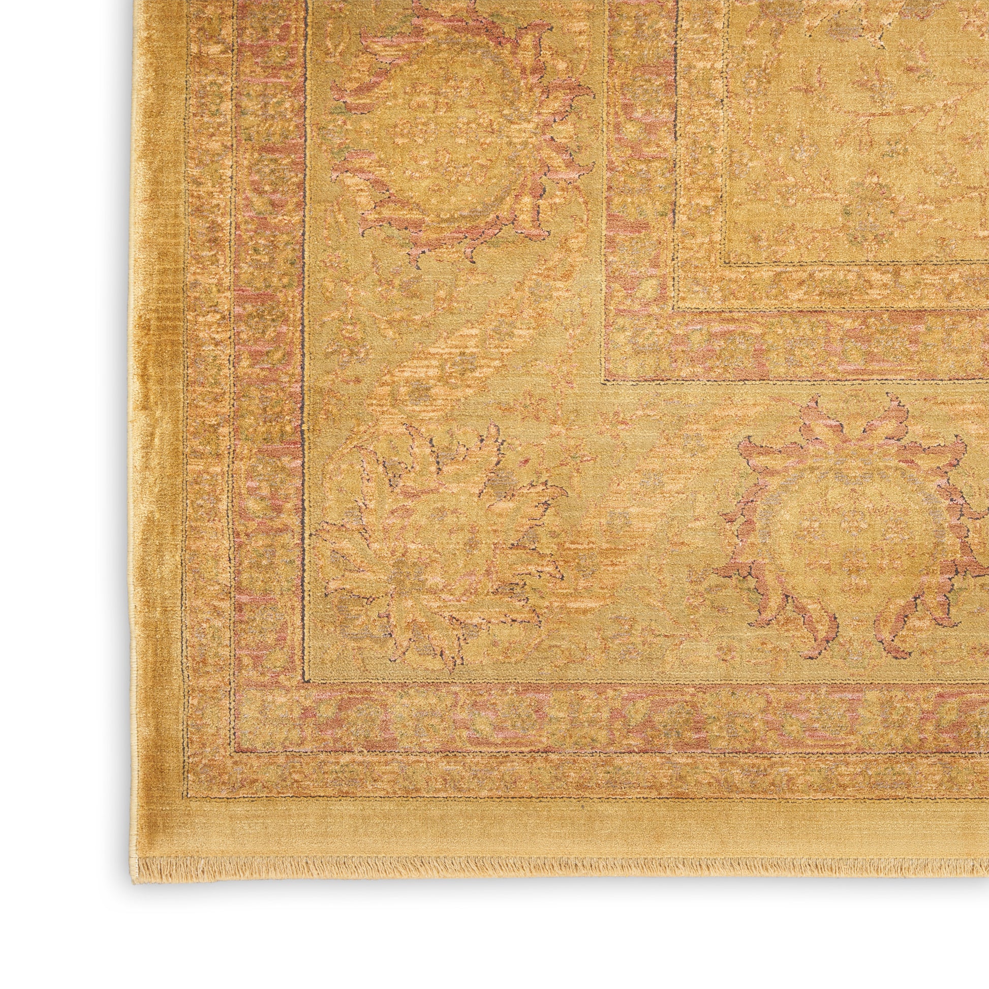 Gold-toned oriental rug corner with pink floral motifs, bordered frames, and fringed edge.