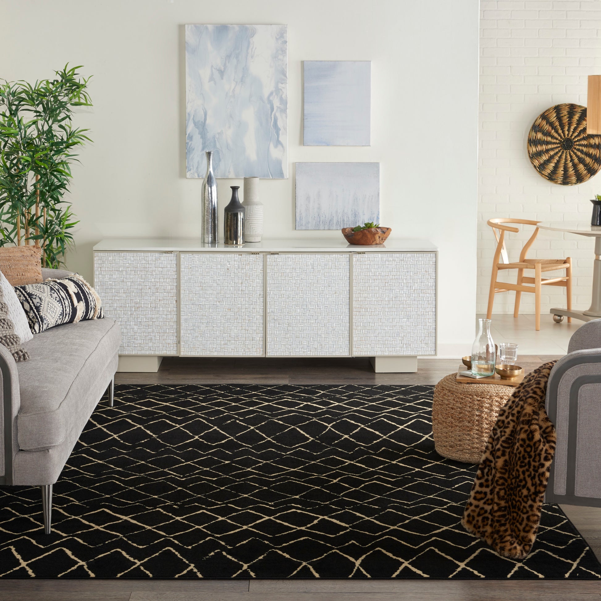 Bright living room with white woven sideboard, blue-gray wall art, gray sofa, black lattice rug, leopard throw, and woven decor.