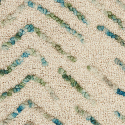Close-up of a cream textured rug with pale blue-green zigzag tufted stripes in a chevron pattern.