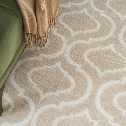 Beige and cream trellis-pattern rug with soft pile beside olive-green sofa and a tan fringed throw.