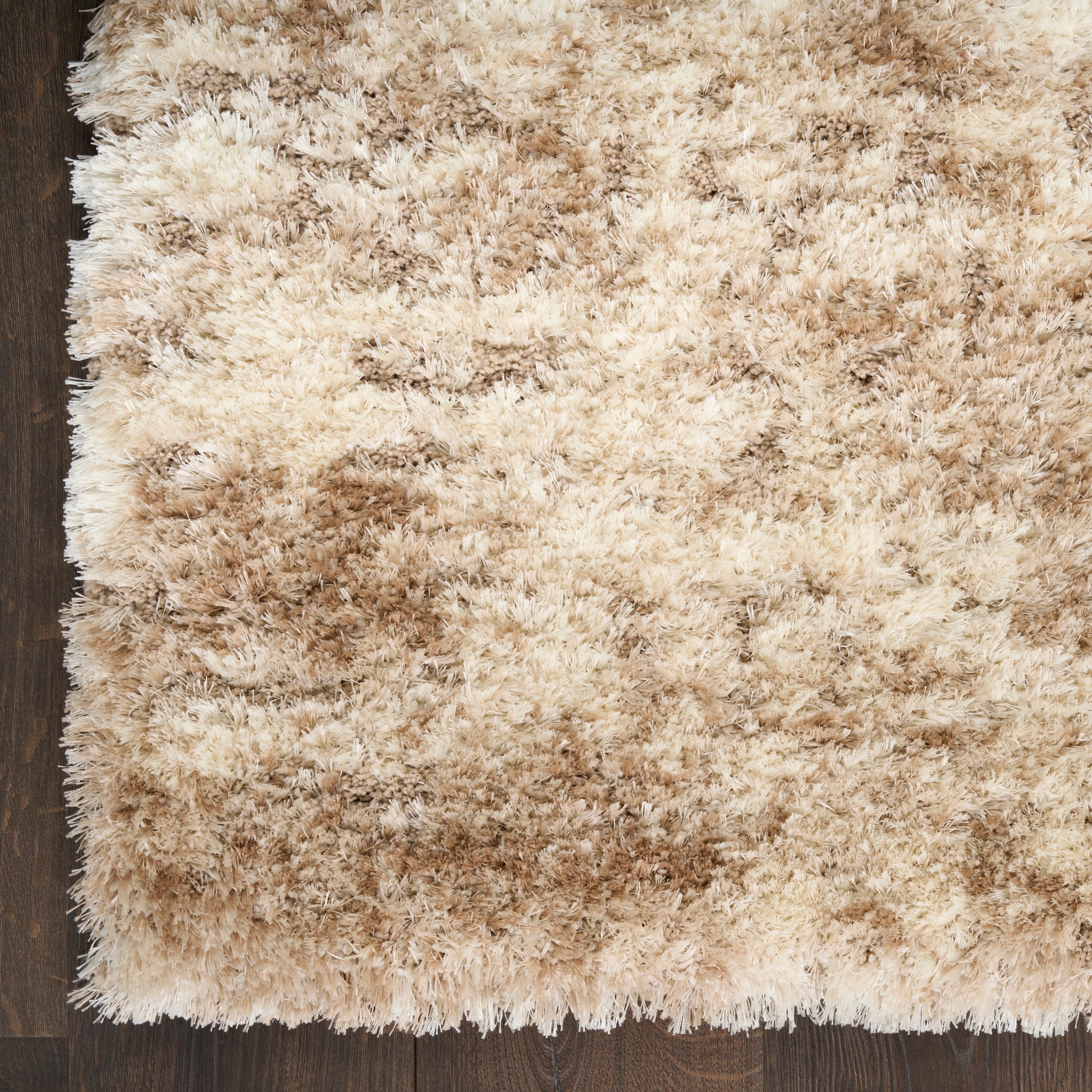 Beige shaggy area rug with cream and tan tones on dark wooden floor; fluffy, rectangular, cozy decor