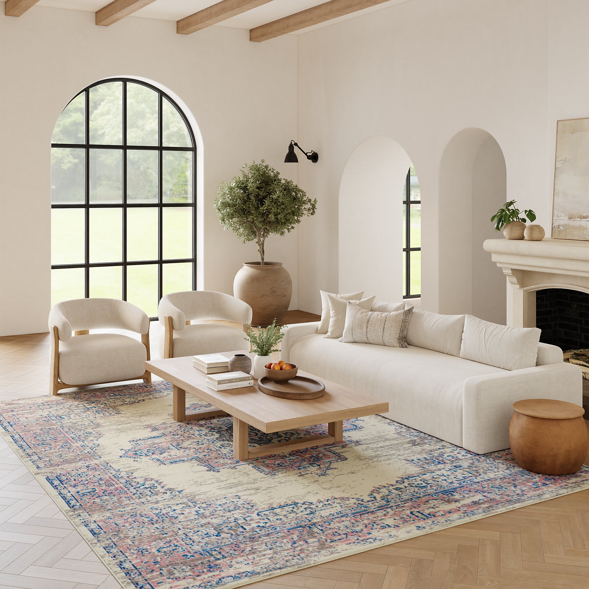 Neutral living room with cream sofa and chairs, wooden coffee table, patterned rug, arched window, potted tree, fireplace.