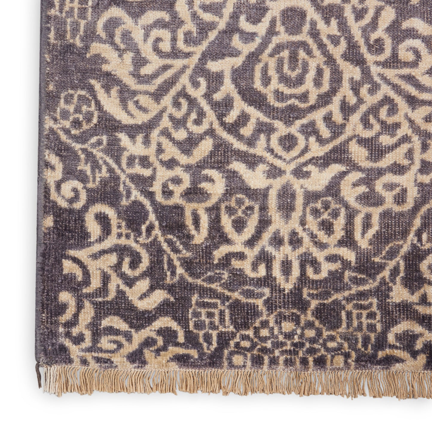 Woven navy rug with a beige traditional damask floral pattern and fringed bottom edge.
