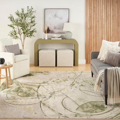 Living room with olive-green console table, ottomans, white armchair, gray sofa, tall plant, abstract art, and leaf rug.