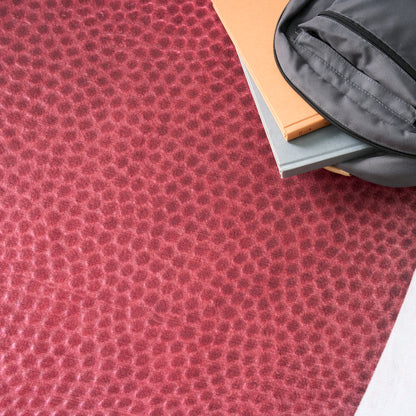 Red pebble-textured fabric background with a gray zippered pouch atop orange and blue notebooks.