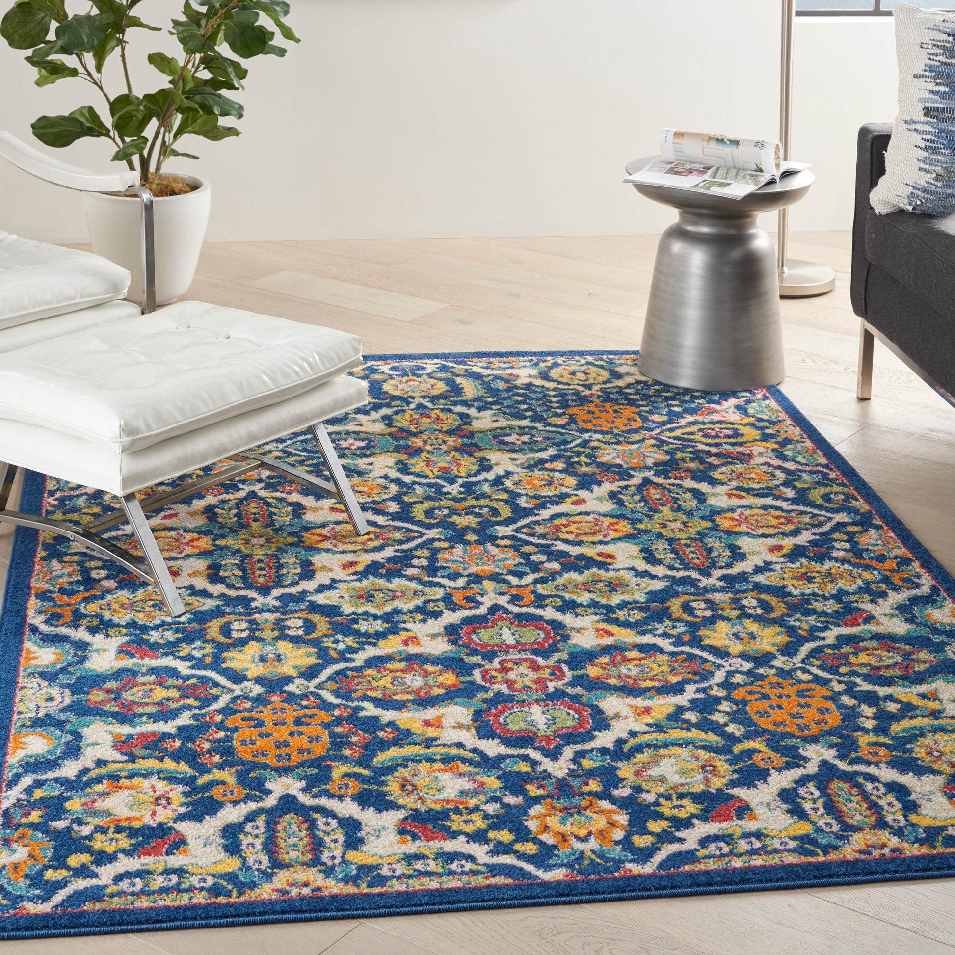 Bohemian-style rug, 5' x 7', with blue base and multicolor floral pattern; white tufted lounge chair and metallic side table in a bright living room.