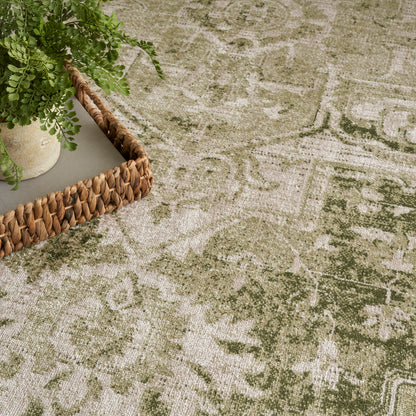 Green & beige vintage-style oriental rug with a woven rattan tray & potted greenery