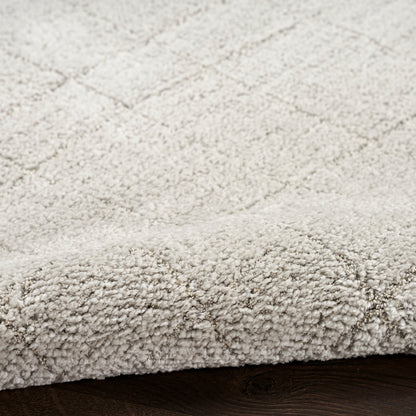 Beige textured rug with a subtle diamond lattice pattern and rolled edge on dark wood floor.