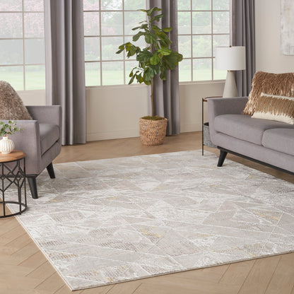 Bright living room with a large pale geometric rug, gray sofas, fur throws, and a potted plant in a wicker basket.