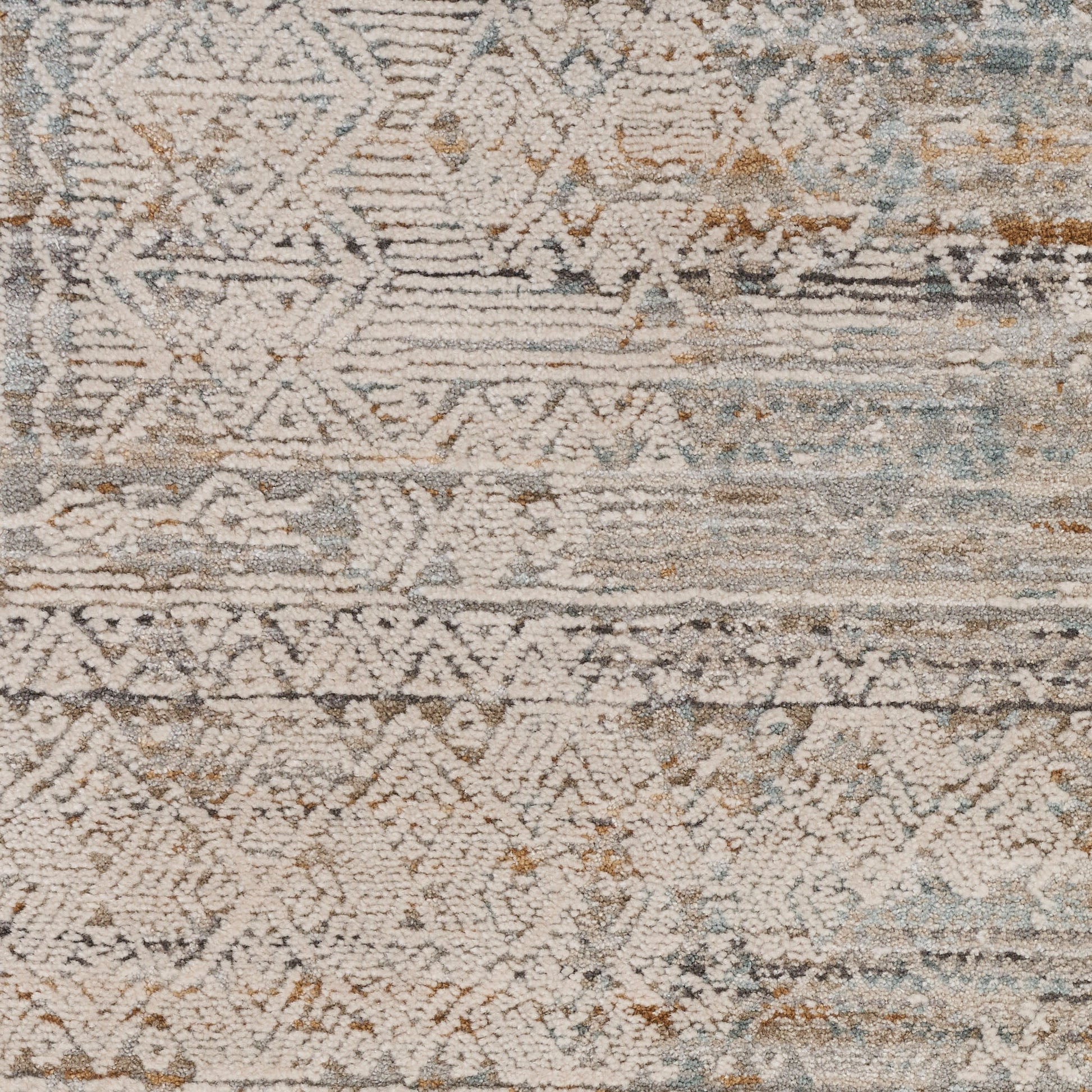 Distressed geometric rug in ivory, beige and pale blue tones with diamond patterns and tribal motifs.