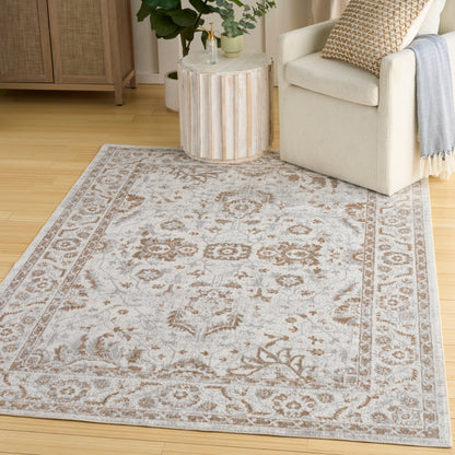 Light gray traditional area rug with tan-brown border medallion pattern, in a cozy living room with beige armchair.