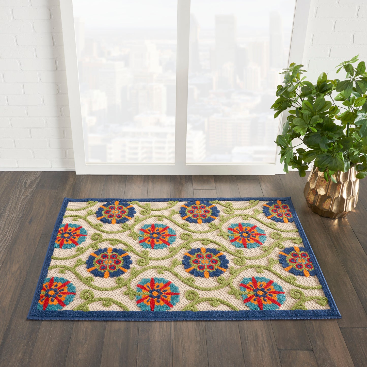 Rectangular oriental-style rug with blue border, cream field, multicolor floral medallions and green vines; near window.