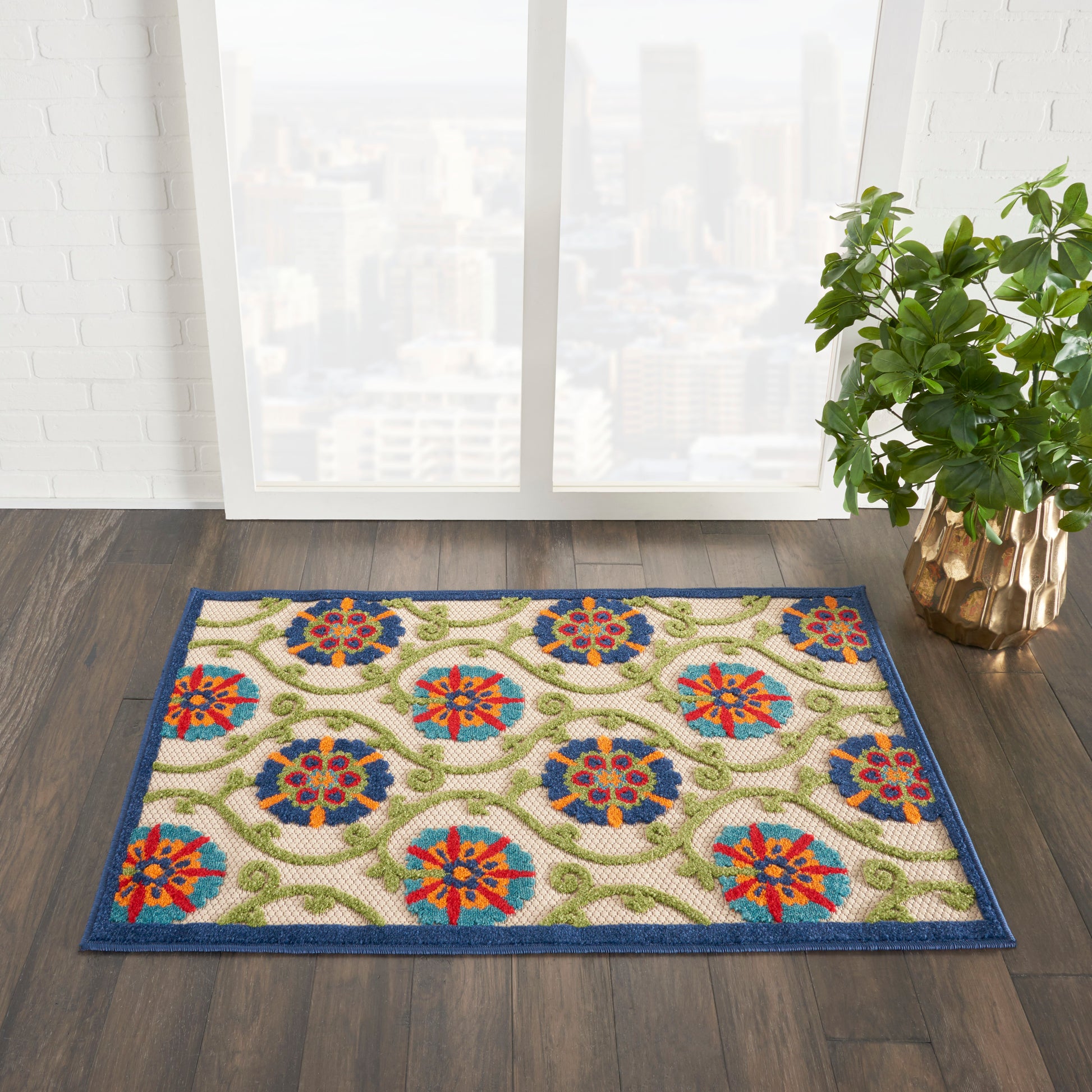Rectangular oriental-style rug with blue border, cream field, multicolor floral medallions and green vines; near window.
