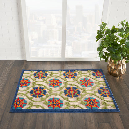 Rectangular oriental-style rug with blue border, cream field, multicolor floral medallions and green vines; near window.