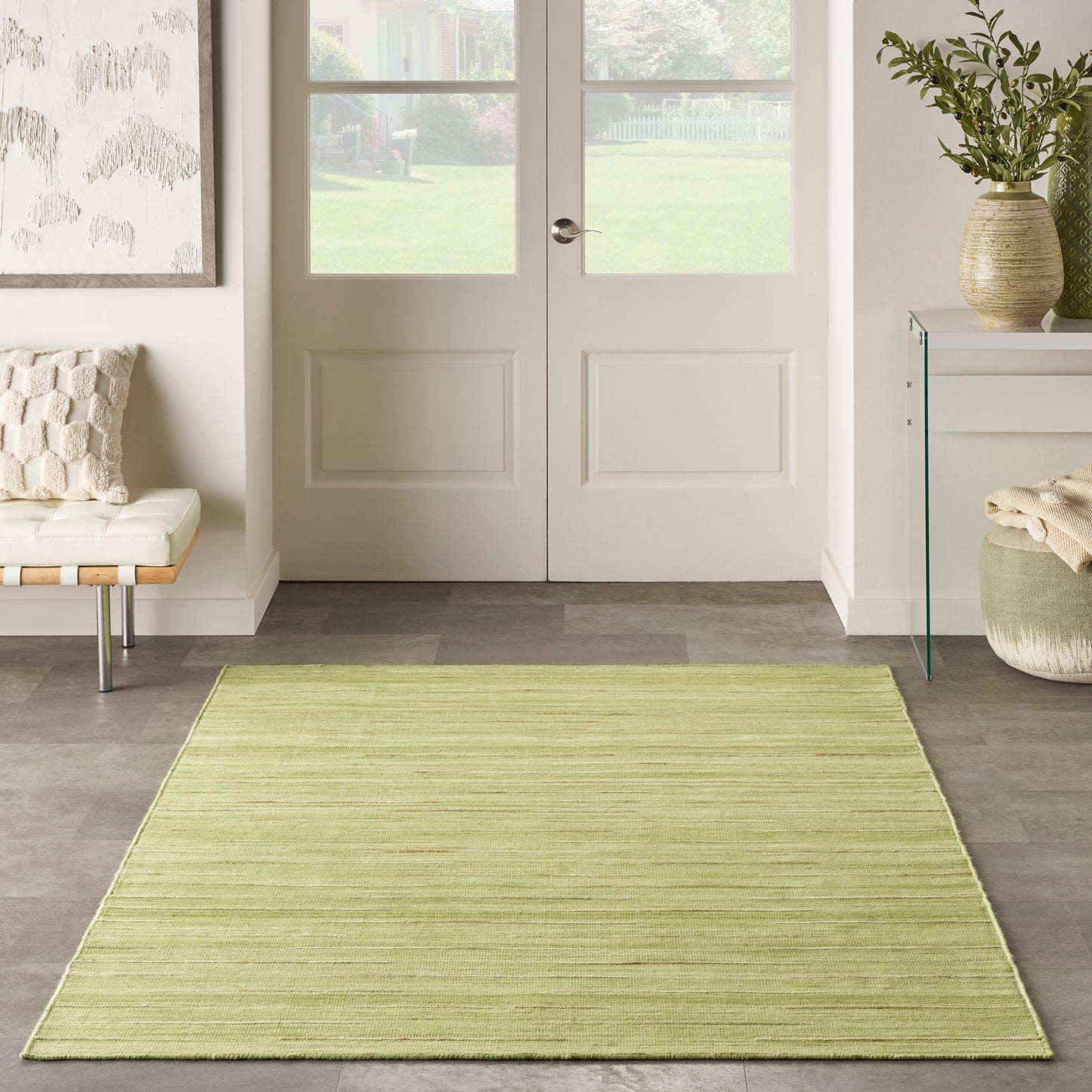 Rectangular light olive-green woven entry rug (6' x 9') on gray tile floor in a bright modern foyer.