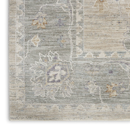 Rectangular traditional area rug with a distressed blue-gray field, ivory floral border, and subtle lavender accents.