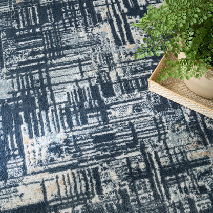 Blue-gray geometric rug with cream accents and a potted fern in a woven tray resting on the edge.