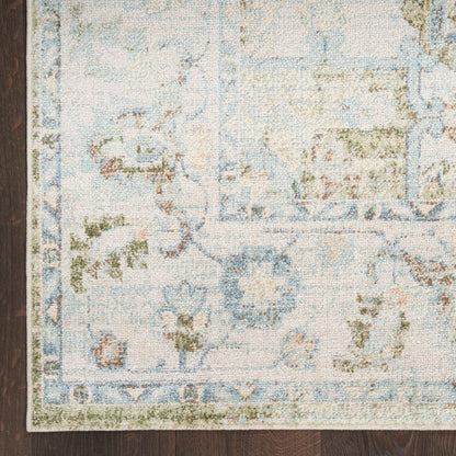 Pastel blue and ivory oriental rug with floral motifs, sage green accents, and blue border on dark wood floor.