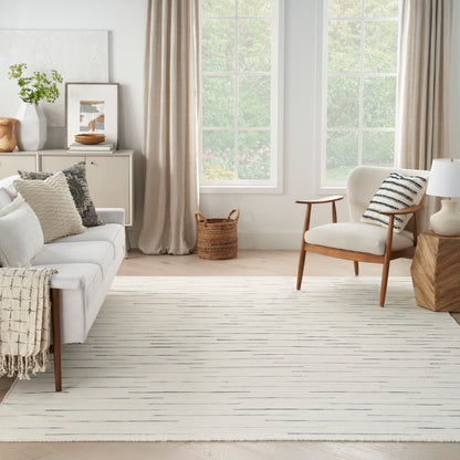 Neutral living room with cream sofa, mid-century wood chair, beige curtains, striped rug, woven basket, plant, framed art.