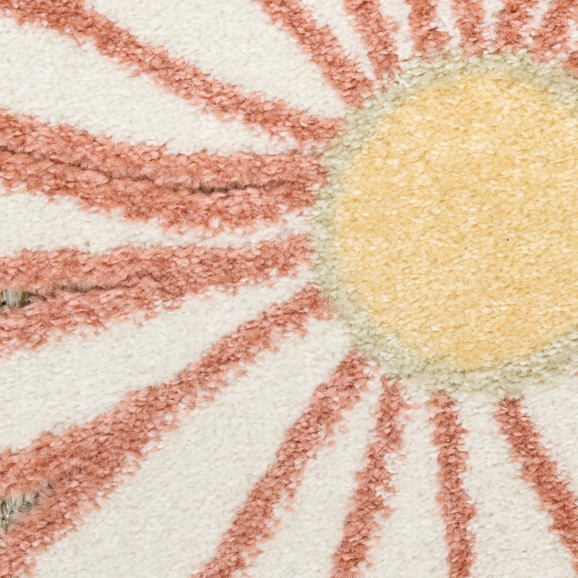 Close-up of a plush sunburst rug: yellow circular center with pink rays on a cream background.