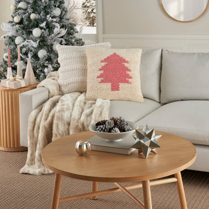 Round light-wood coffee table with star sculpture & pinecone bowl; beige sofa with knit pillow & cozy throw.