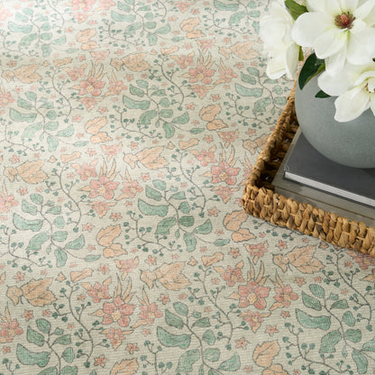 Pastel floral patterned rug with mint green leaves and peach blossoms; wicker tray with books and a vase of white flowers.