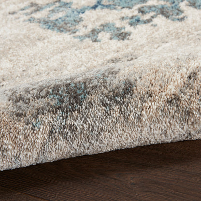 Soft high-pile area rug in beige-gray with blue accents; plush tufted texture.