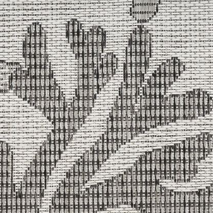 Close-up of a woven rug with gray and charcoal geometric leaf-like motif on a light background.