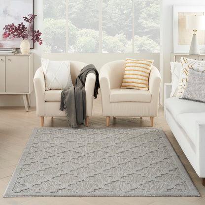 Rectangular light gray woven area rug with a subtle geometric chevron pattern in a bright living room with cream sofas.