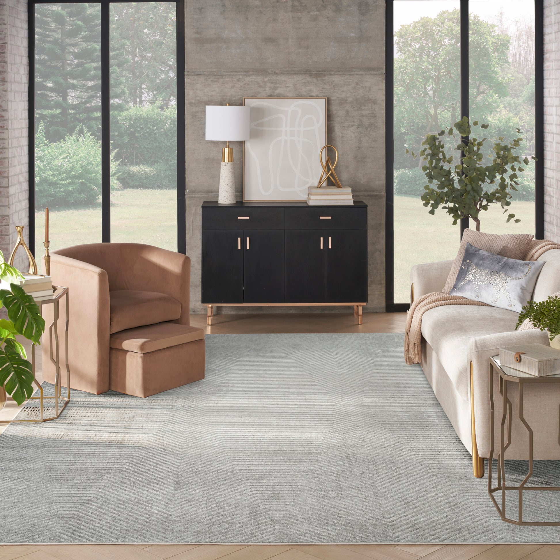 Vintage 8' x 10' rug in a modern living room with a peach velvet armchair, beige sofa, black sideboard, gold accents, and large windows.