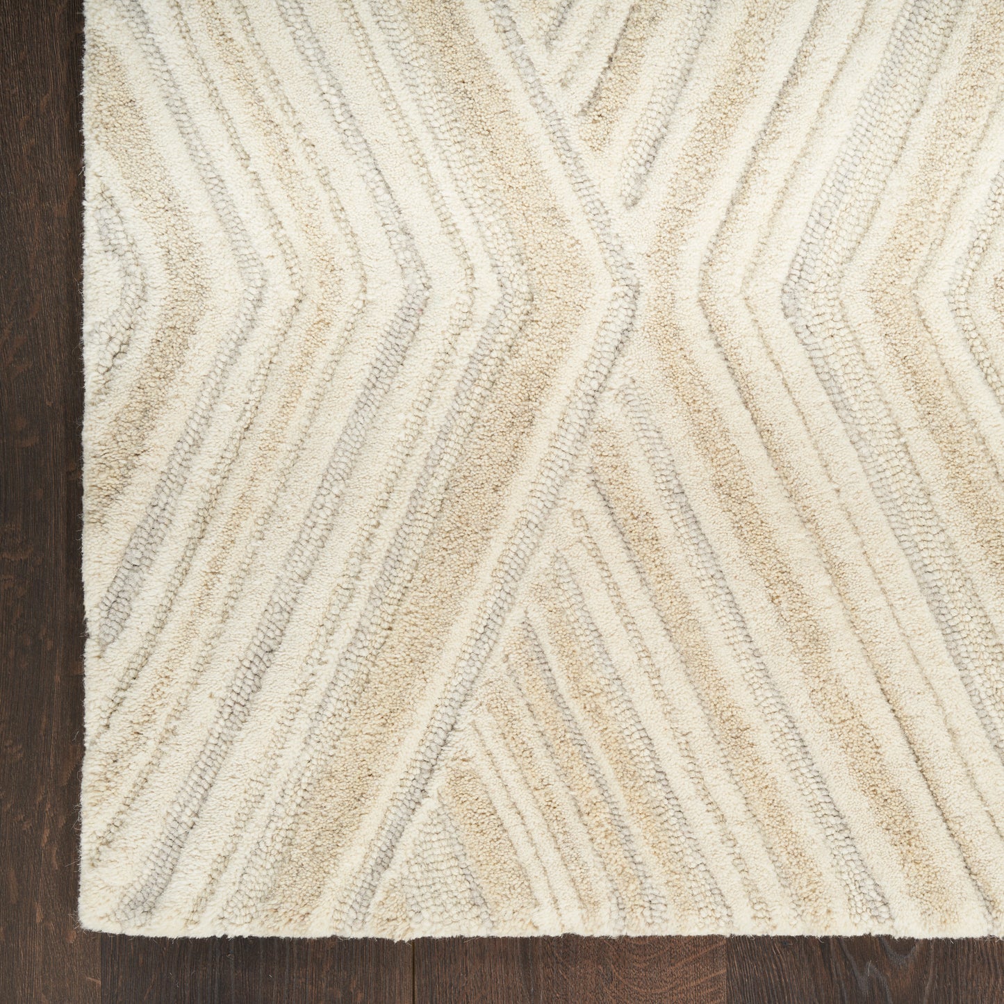 Beige and cream shag rug with chevron stripe pattern on dark wood floor.