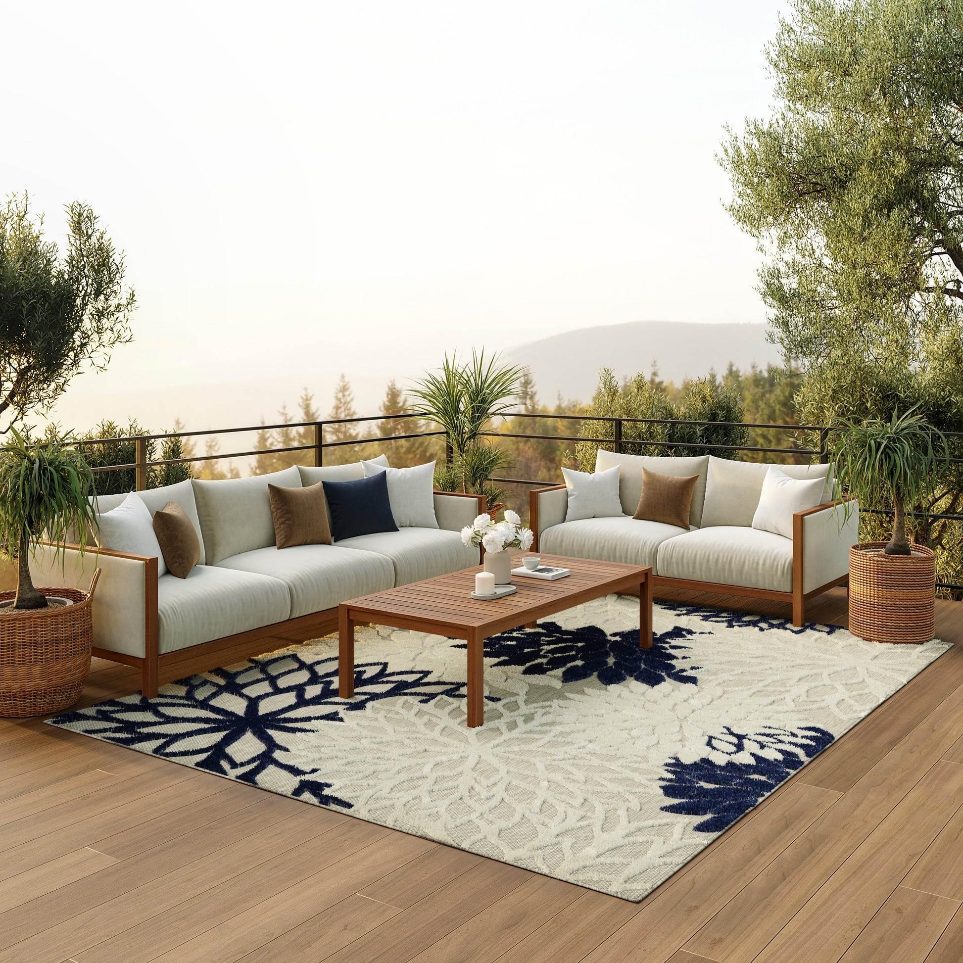 Outdoor wooden-framed sectional with beige cushions, navy pillows, coffee table, potted plants, and a blue floral rug.