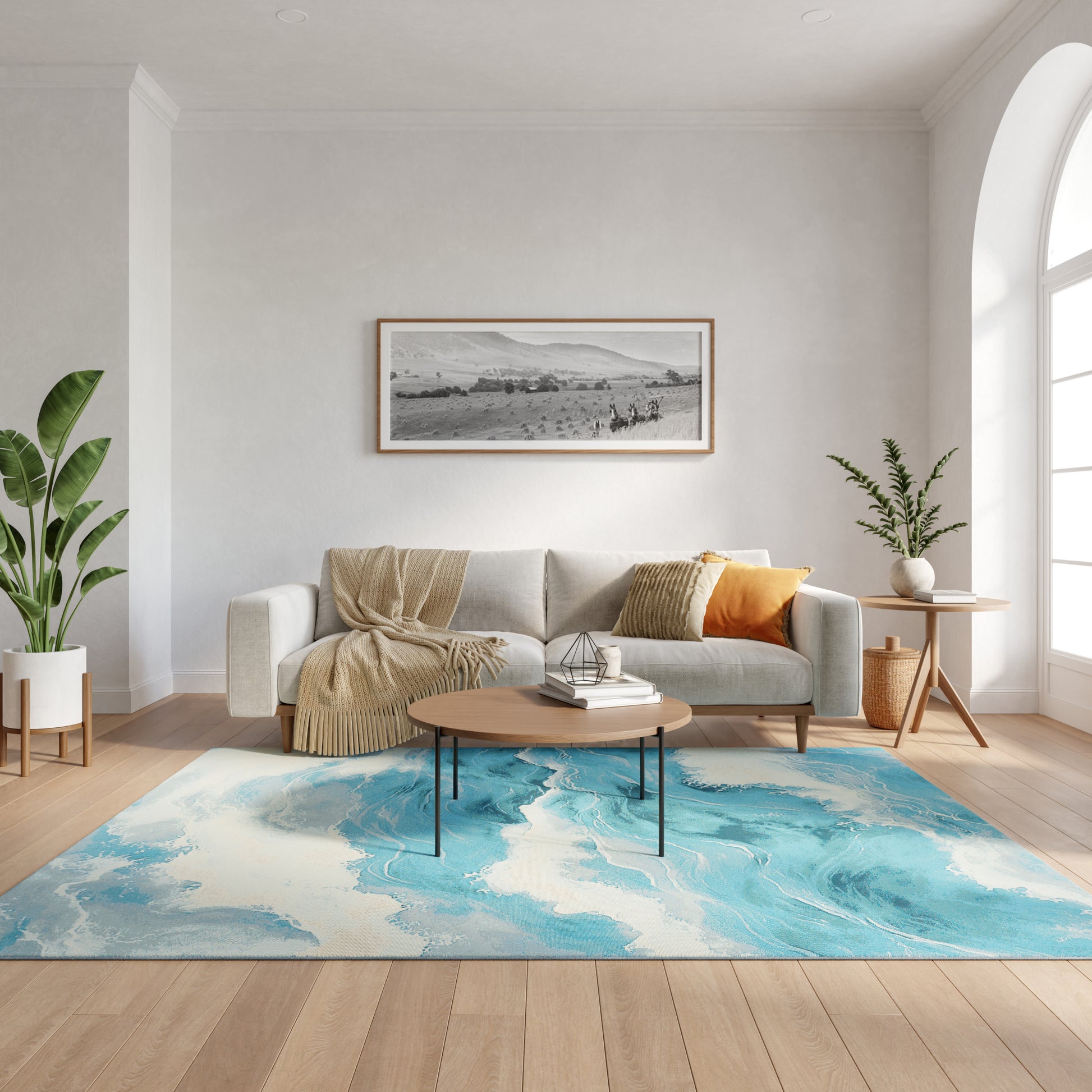 Modern living room with light sofa, beige throw, orange pillow, round wood coffee table, blue rug, potted plants.
